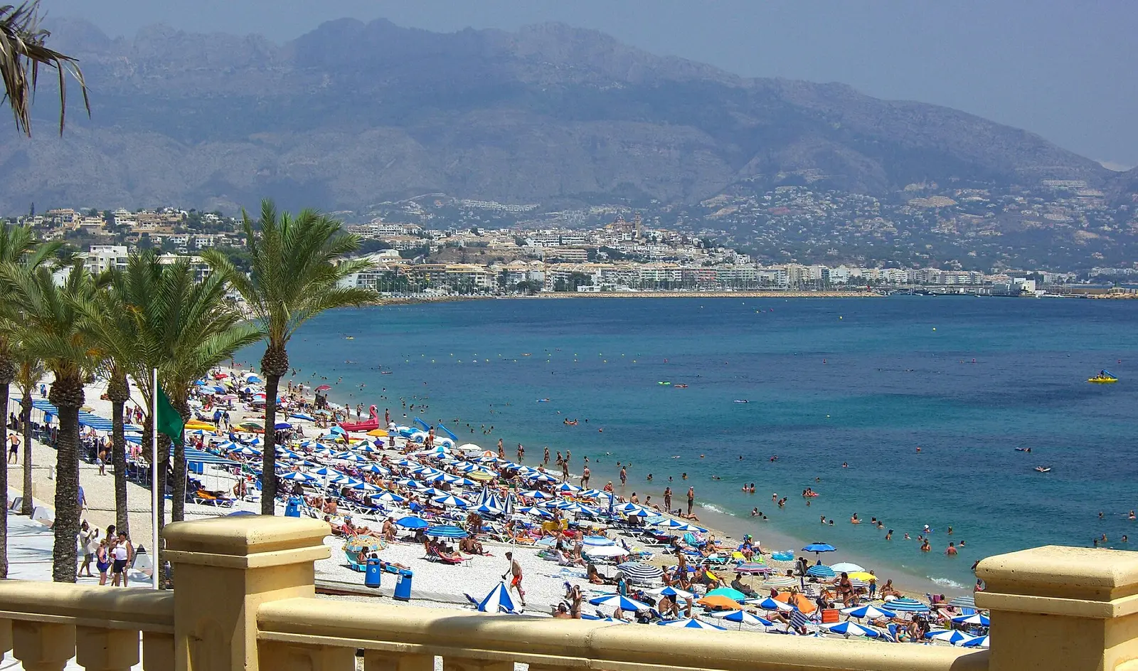Het strand van Albir op een zomerse dag, met parasols en turquoise water