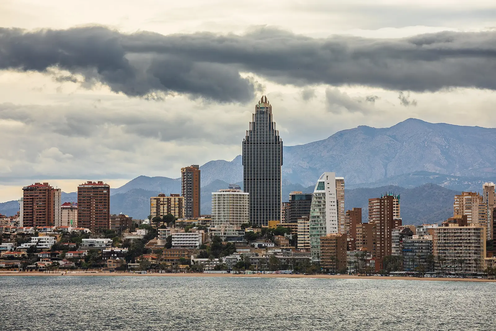 De skyline van Benidorm aan het strand, met de bergen erachter