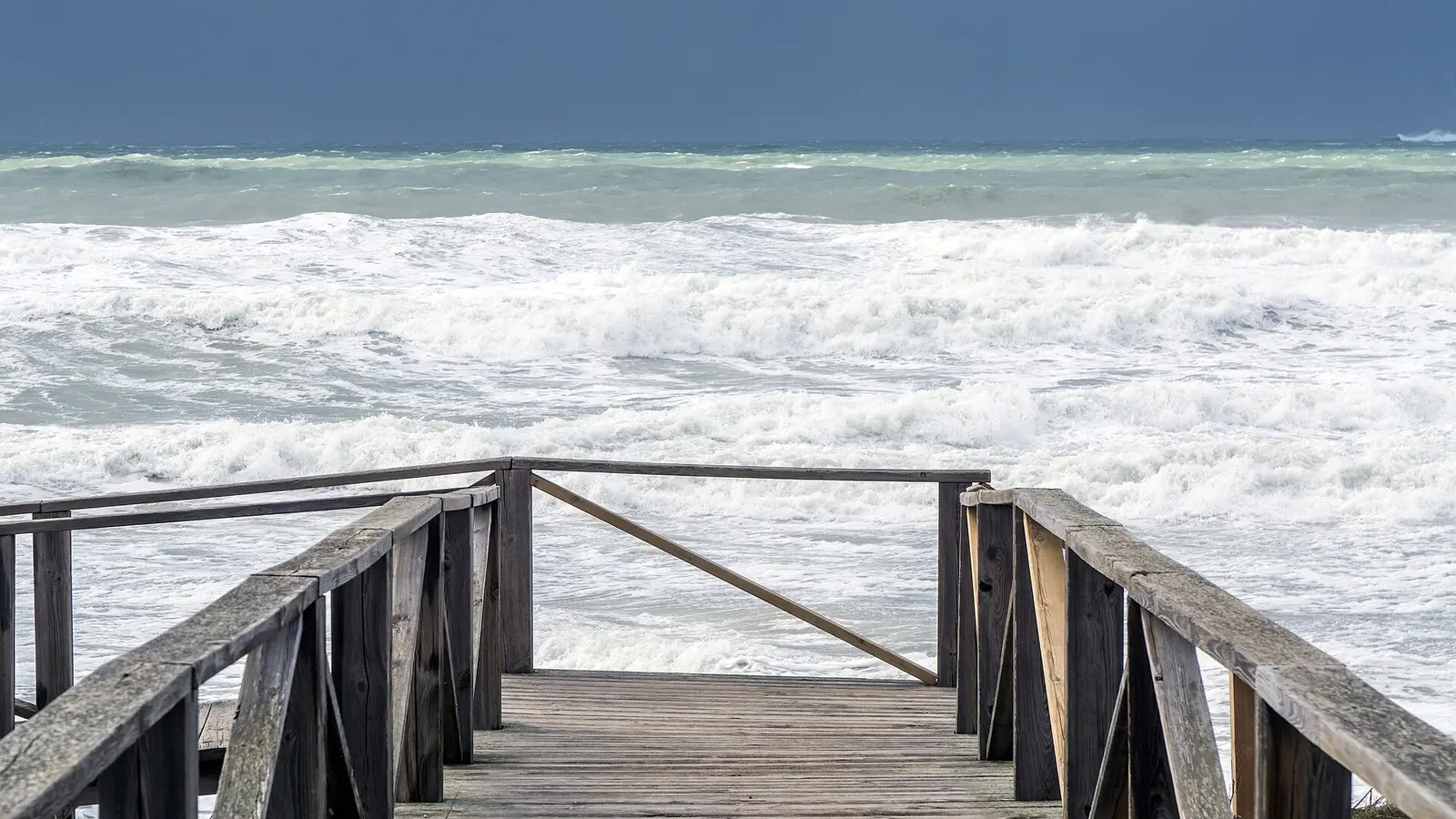 Een houten vlonder naar het wijde strand van de Costa de la Luz
