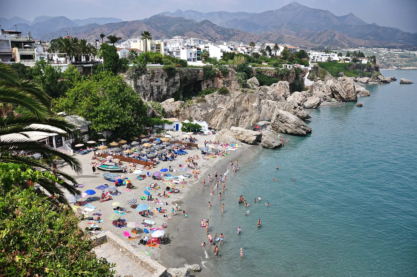 Een druk strand aan de Costa del Sol tussen de rotsen