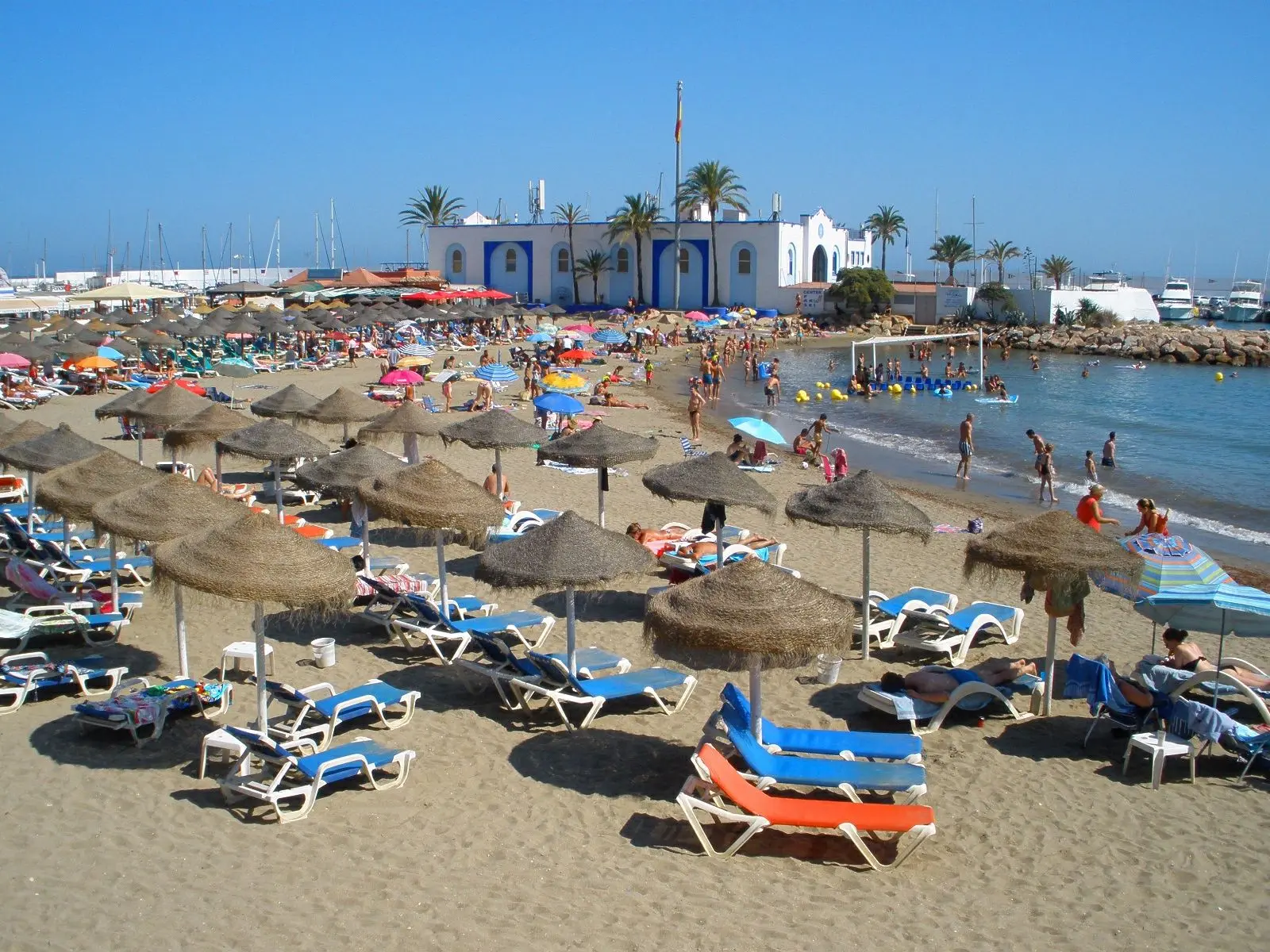 Een strand bij Marbella met rieten parasols en een beachclub