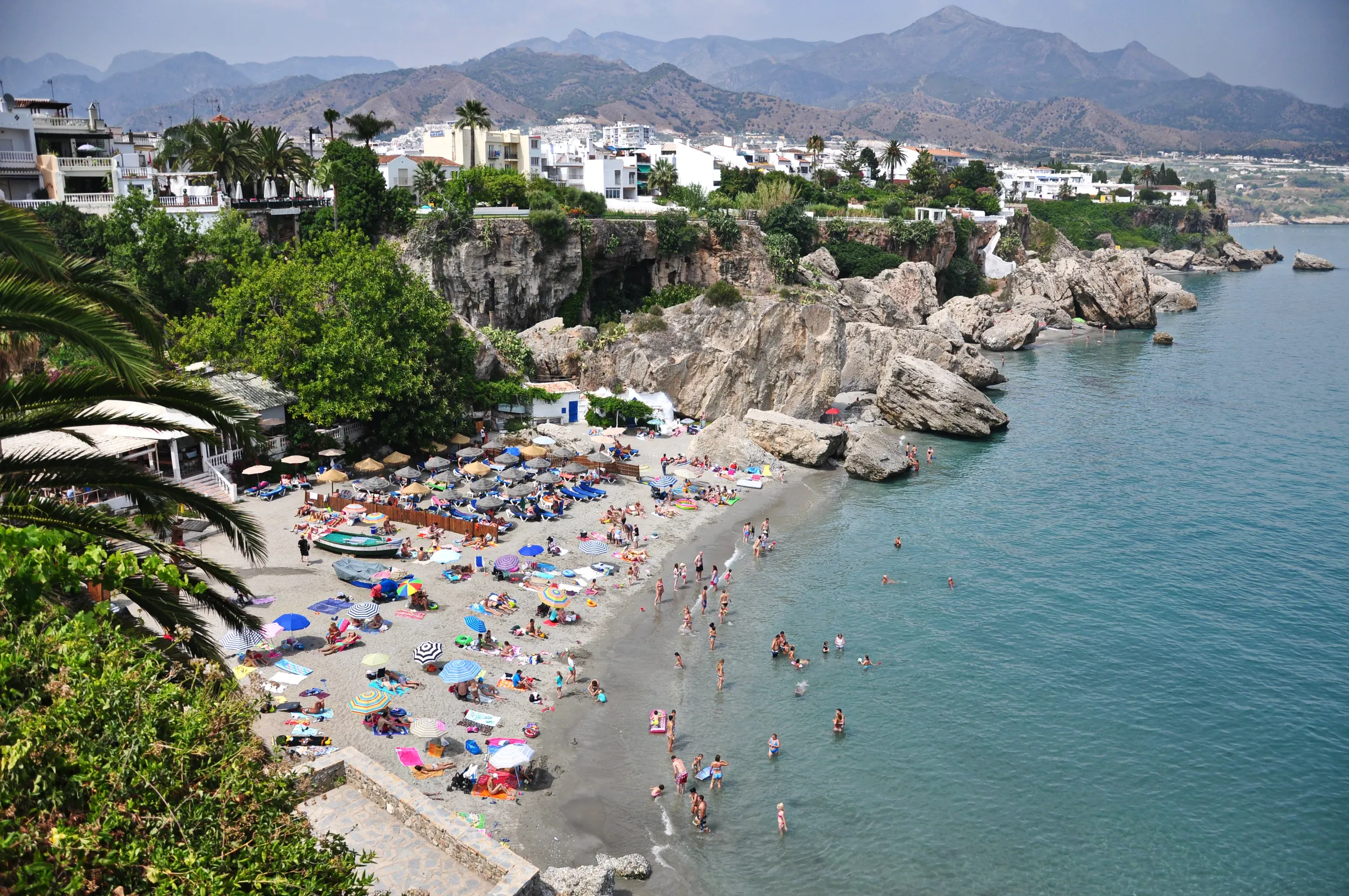 Een druk strand aan de Costa del Sol tussen de rotsen